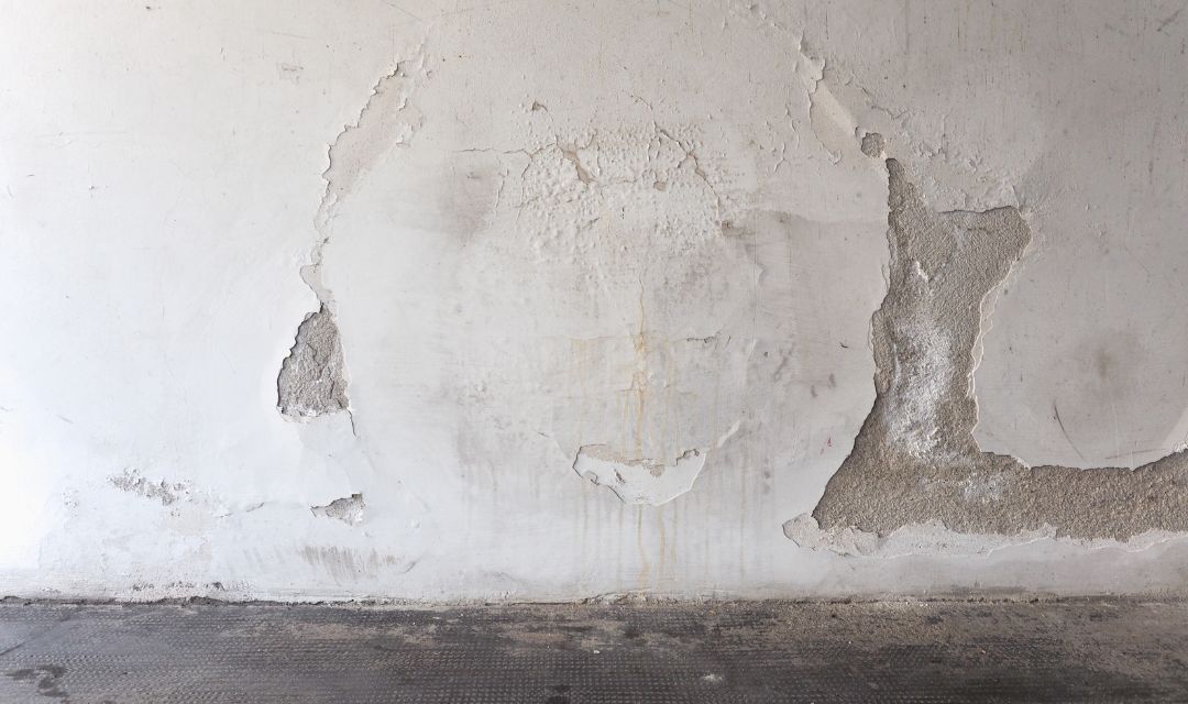 Hausfassade mit abplatzendem Putz im Sockelbereich